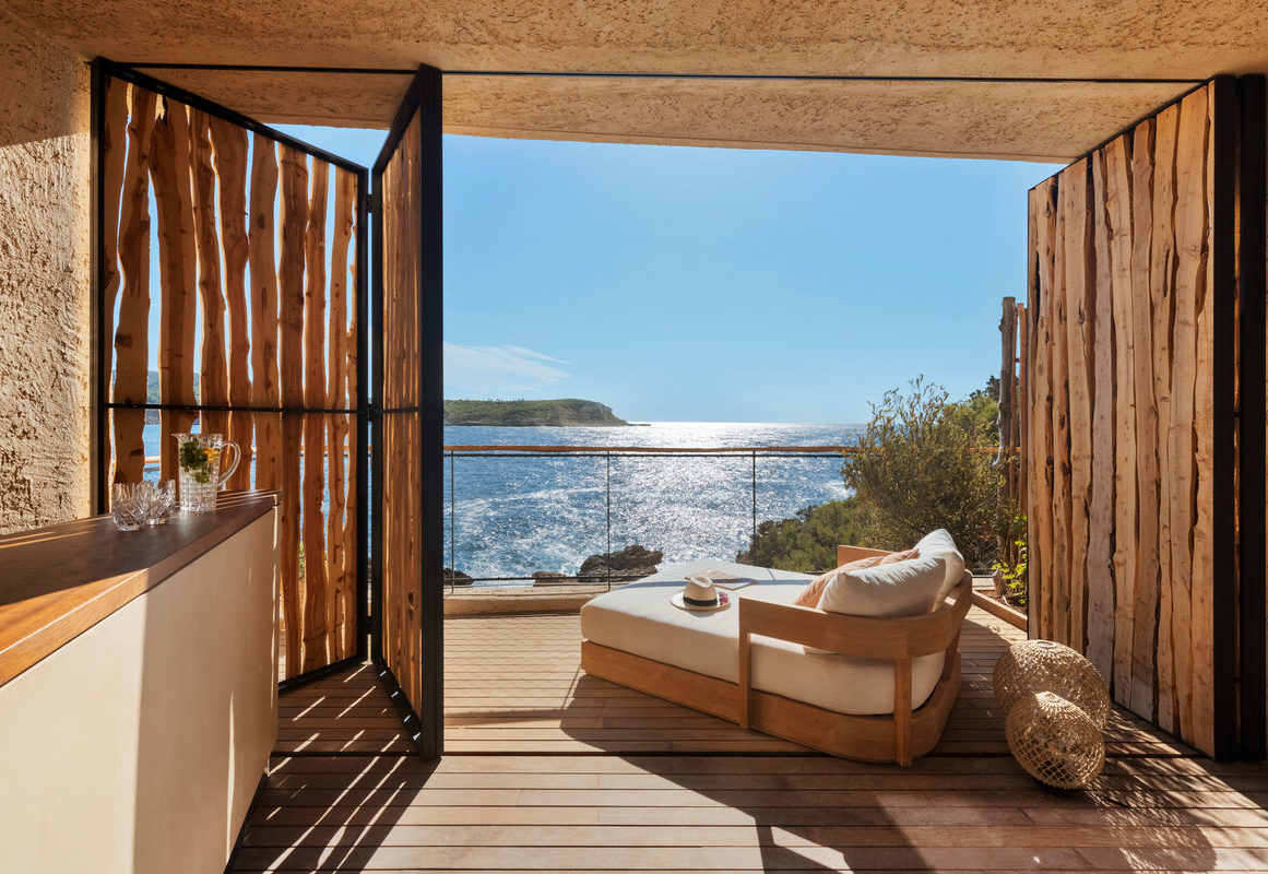 a deck with a chair and a table and a table with a view of the ocean