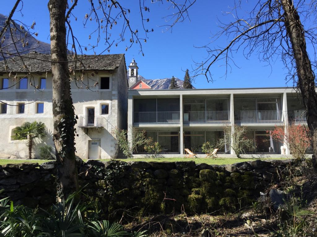 a building with a stone wall and trees